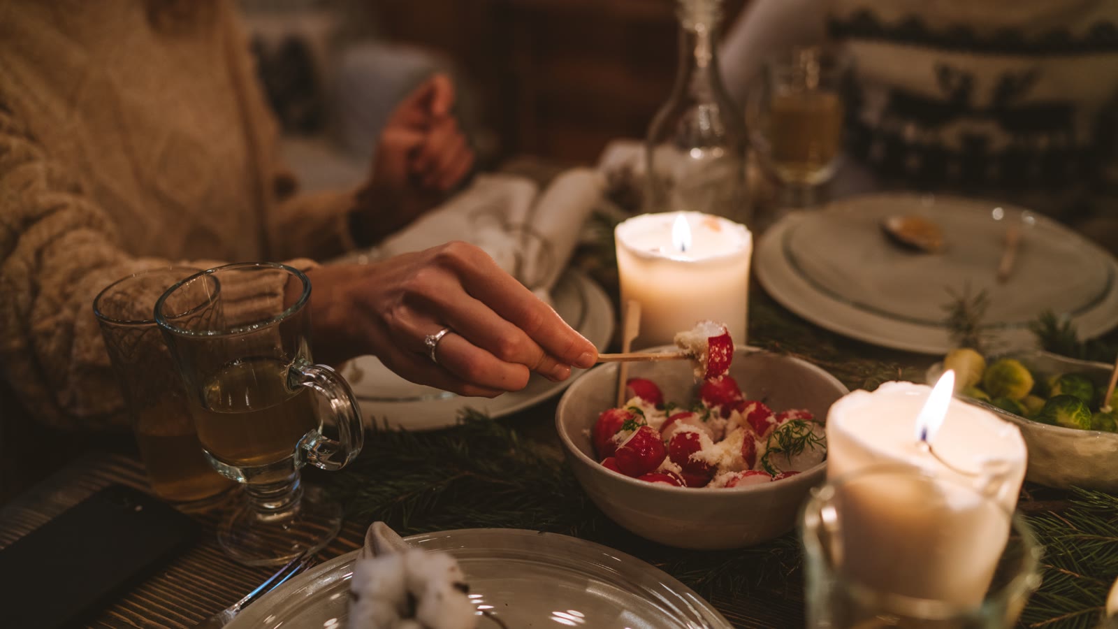 Julefrokostbord i levende lys med skål, glas og tallerkener