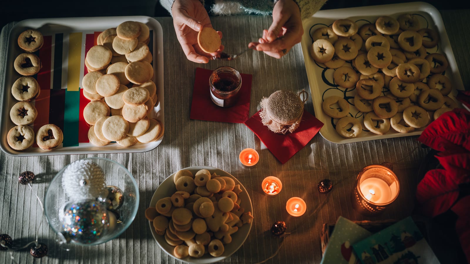 Hjemmebagte julesmåkager på bageplader mellem levende lys og julepynt