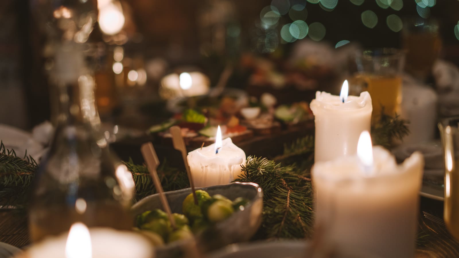 Julebord med levende lys, grangrene og små skåle med tilbehør