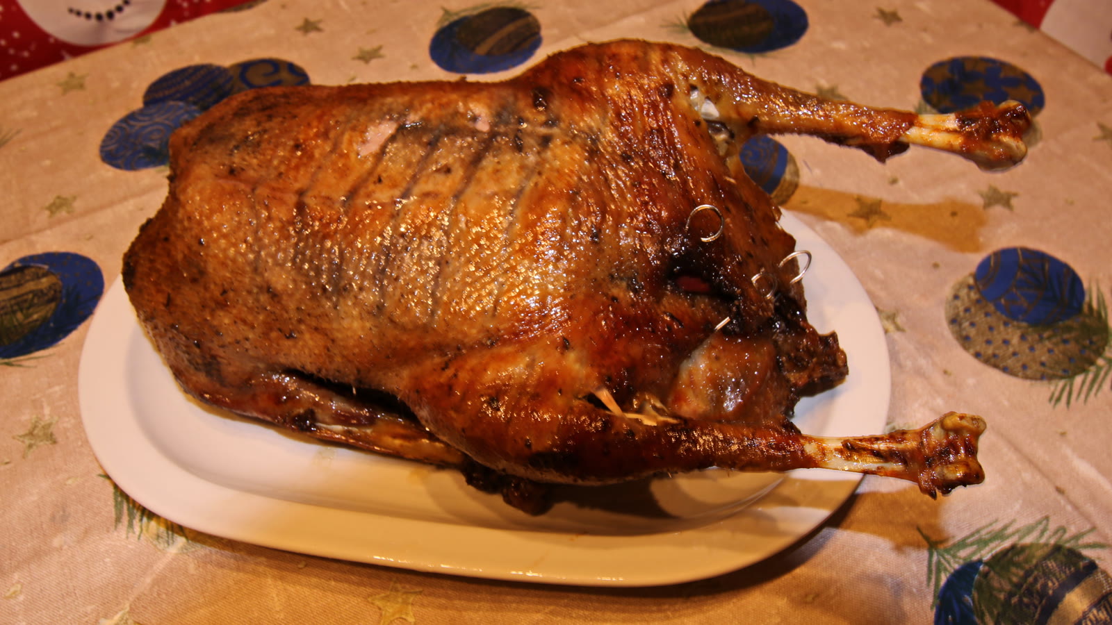 Hel stegt fugl med sprødt skind på fad på et pyntet julebord
