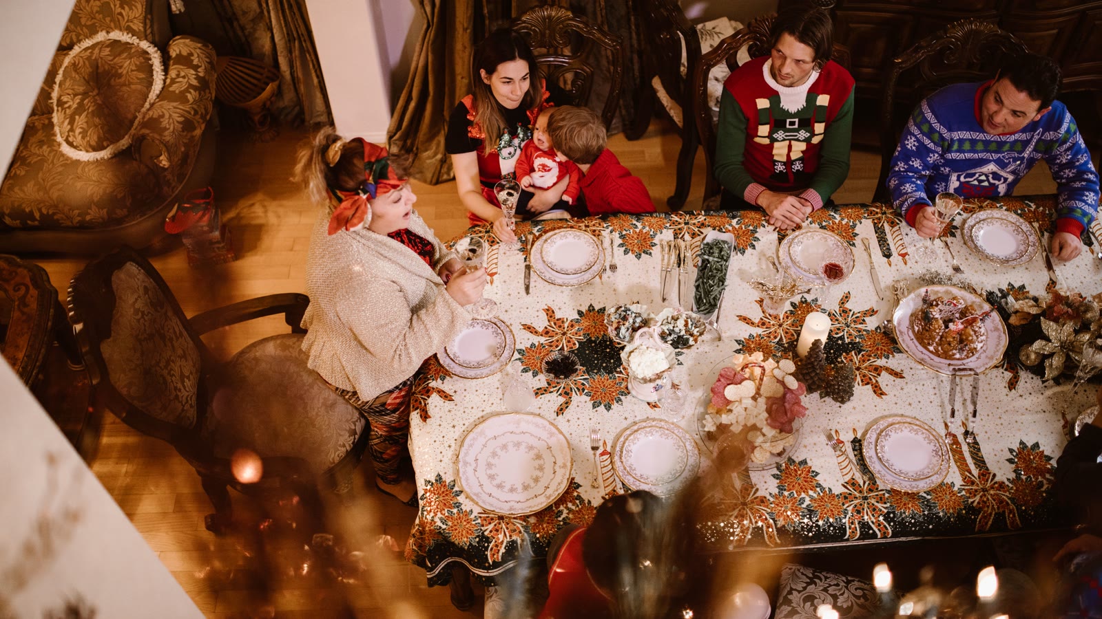 Selskab samlet omkring et langt, pyntet julebord efter middagen